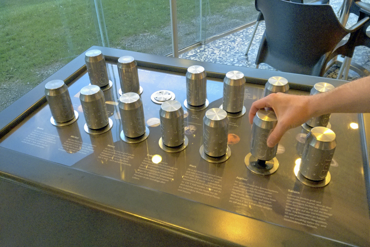 Das Foto zeigt ein Experiment im Eingangsbereich des Zeiss Planetariums in Bochum, mit dem anhand von Dosen die Schwerkraft auf verschiedenen Planeten für Besucher erlebbar gemacht wird.
