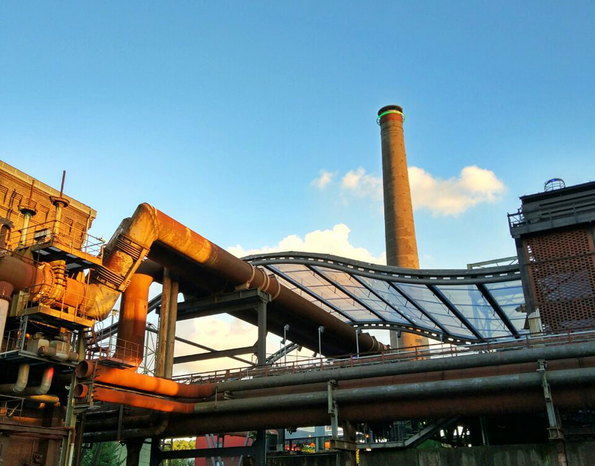 Das Bild zeigt die Industriekulisse und das Glasdach im Landschaftspark Duisburg-Nord