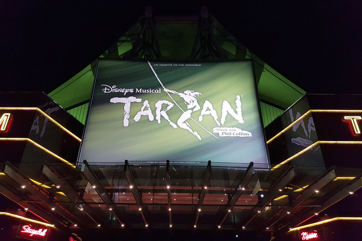 Das Foto zeigt das Stage Metronom Theater samt Tarzanplakat bei Nacht
