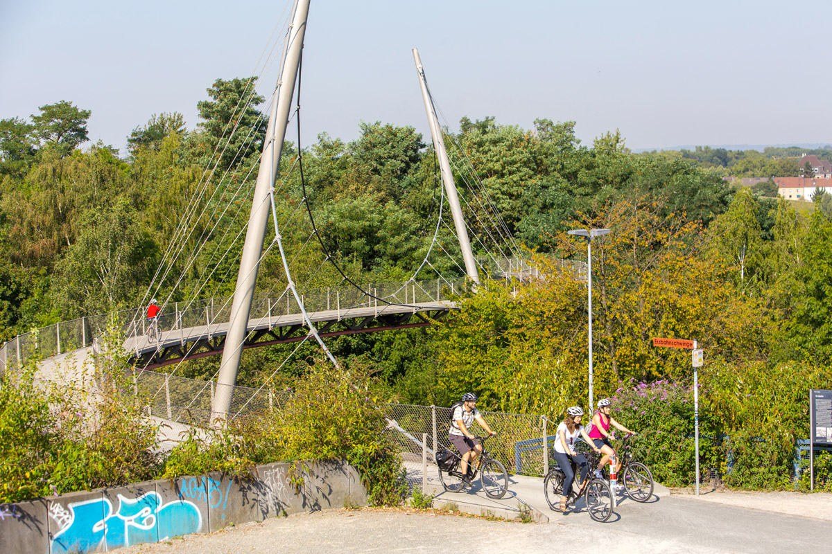 Das Foto zeigt Radfahrer auf der Erzbahntrasse im Westpark an der Jahrhunderthalle Bochum