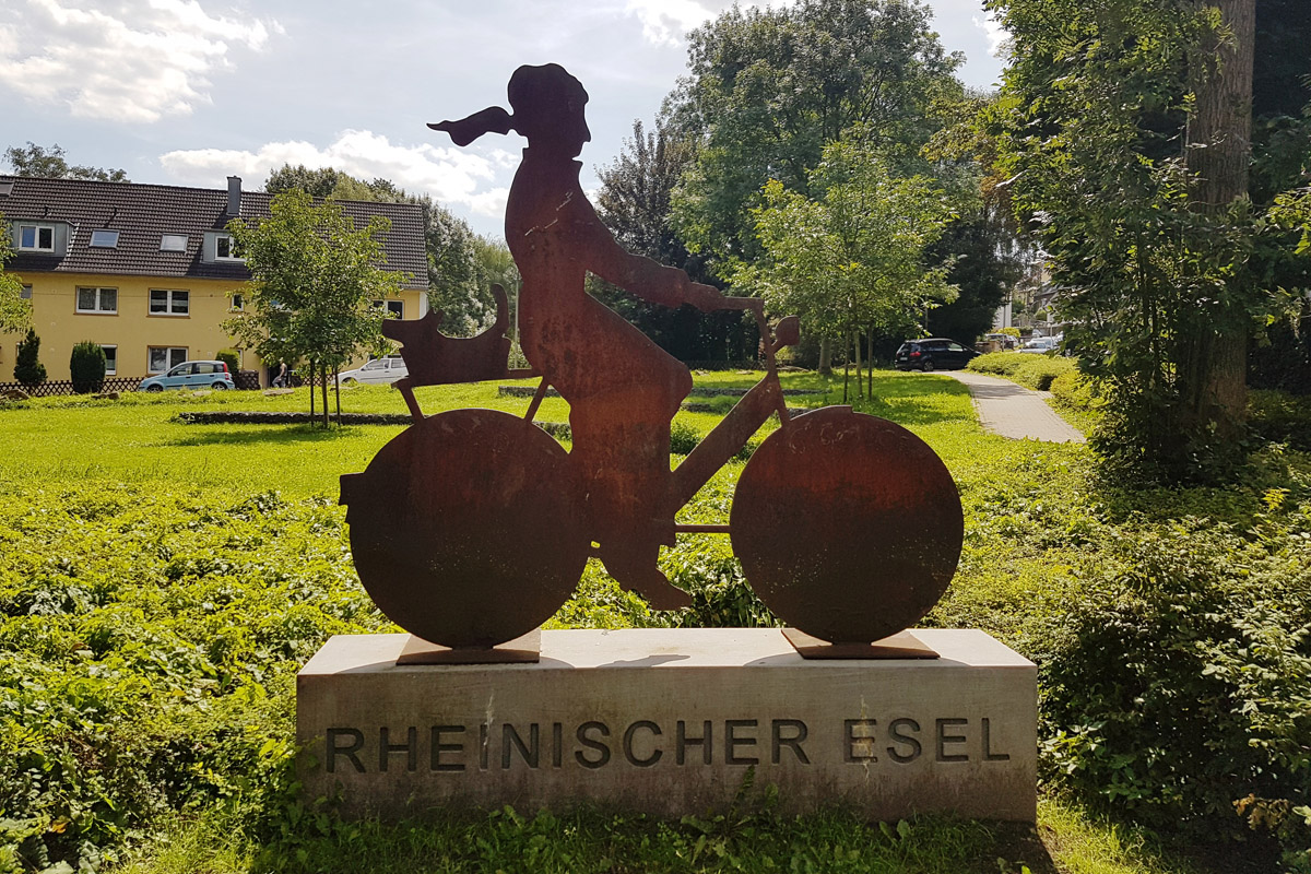 Das Foto zeigt eine Figur einer Radfahrerin auf dem rheinischen Esel