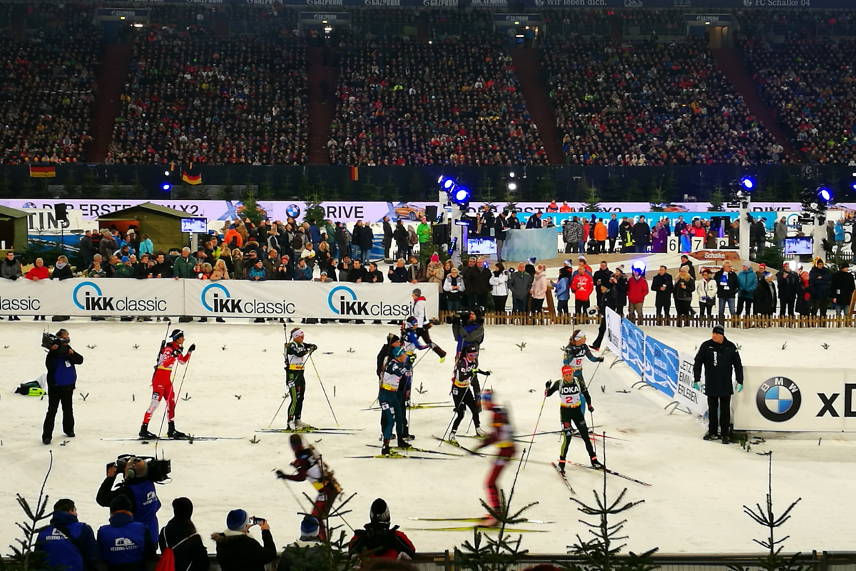 Das Bild zeigt die Übergabe des Staffelstabs beim Biathlon auf Schalke