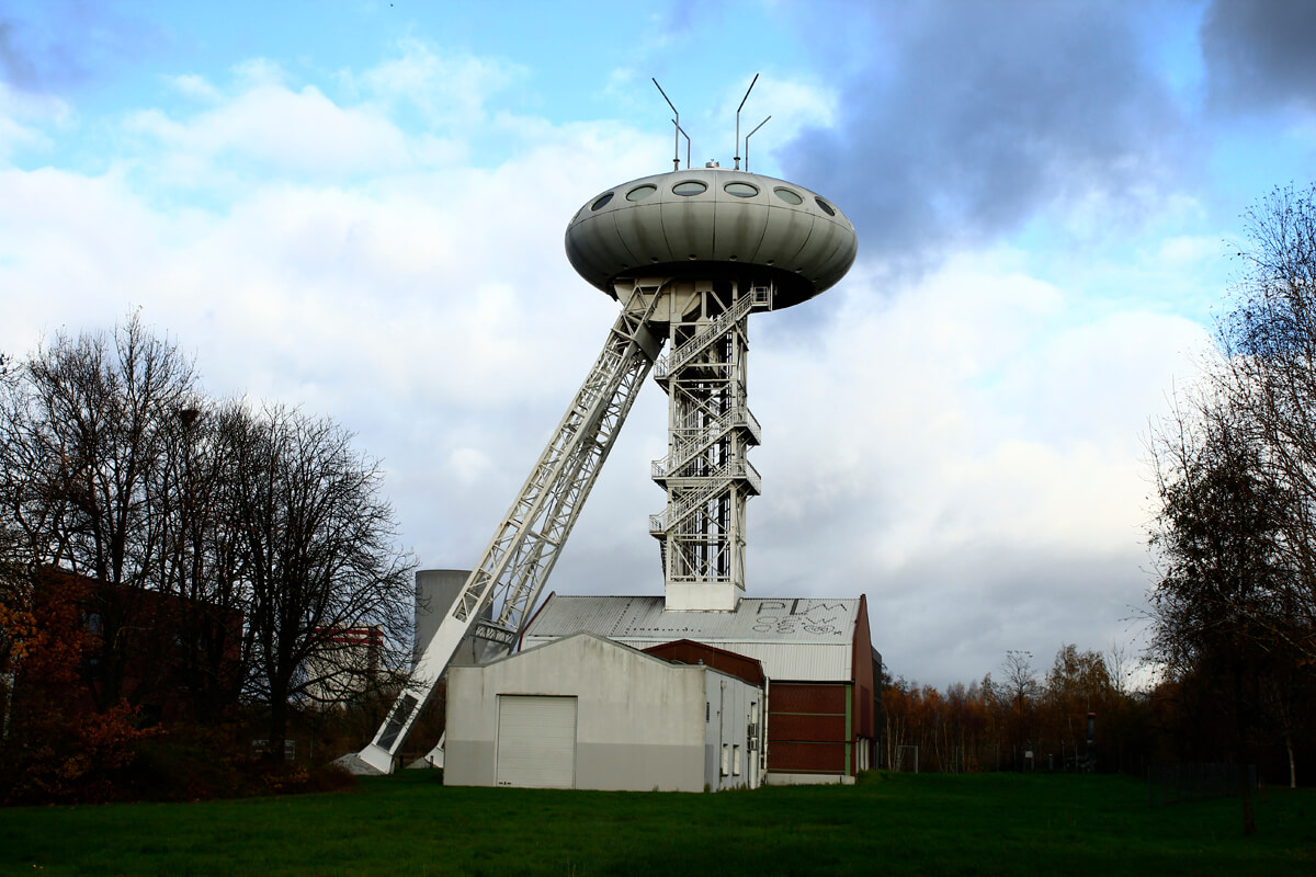 Das Bild zeigt einen Zechenturm auf dem ein Ufo-artiges Gebilde angebracht ist.