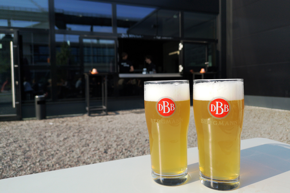 Zwei Gläser mit frisch Gezapftem Bier vor der Kulisse der Bergmann Brauerei