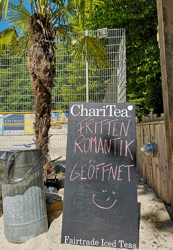 Das Foto zeigt eine Tafel mit der Aufschrift Fritten Romantik im StrandDeck Kemnade am Kemnader See, einem der vielen Beach Clubs im Ruhrgebiet