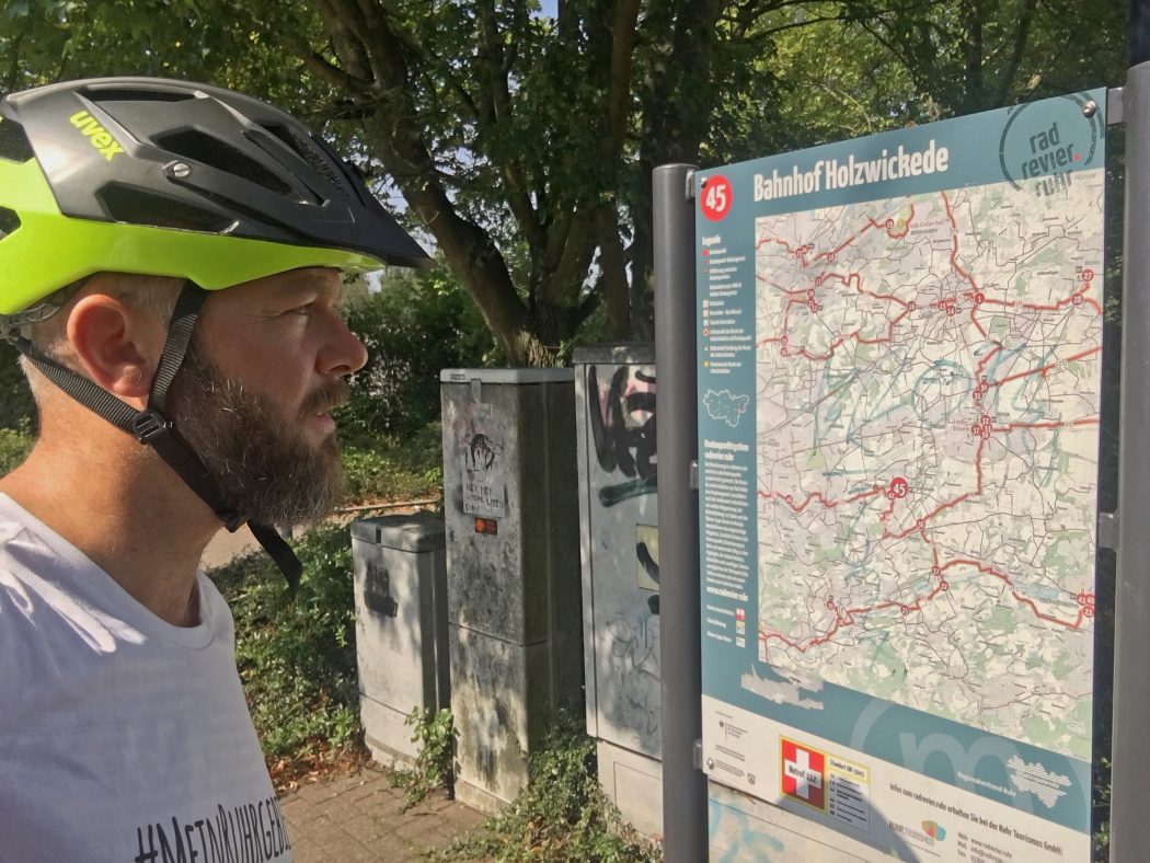 Das Foto zeigt einen Radfahrer vor einem Schild des Knotenpunktsystems im radrevier.ruhr