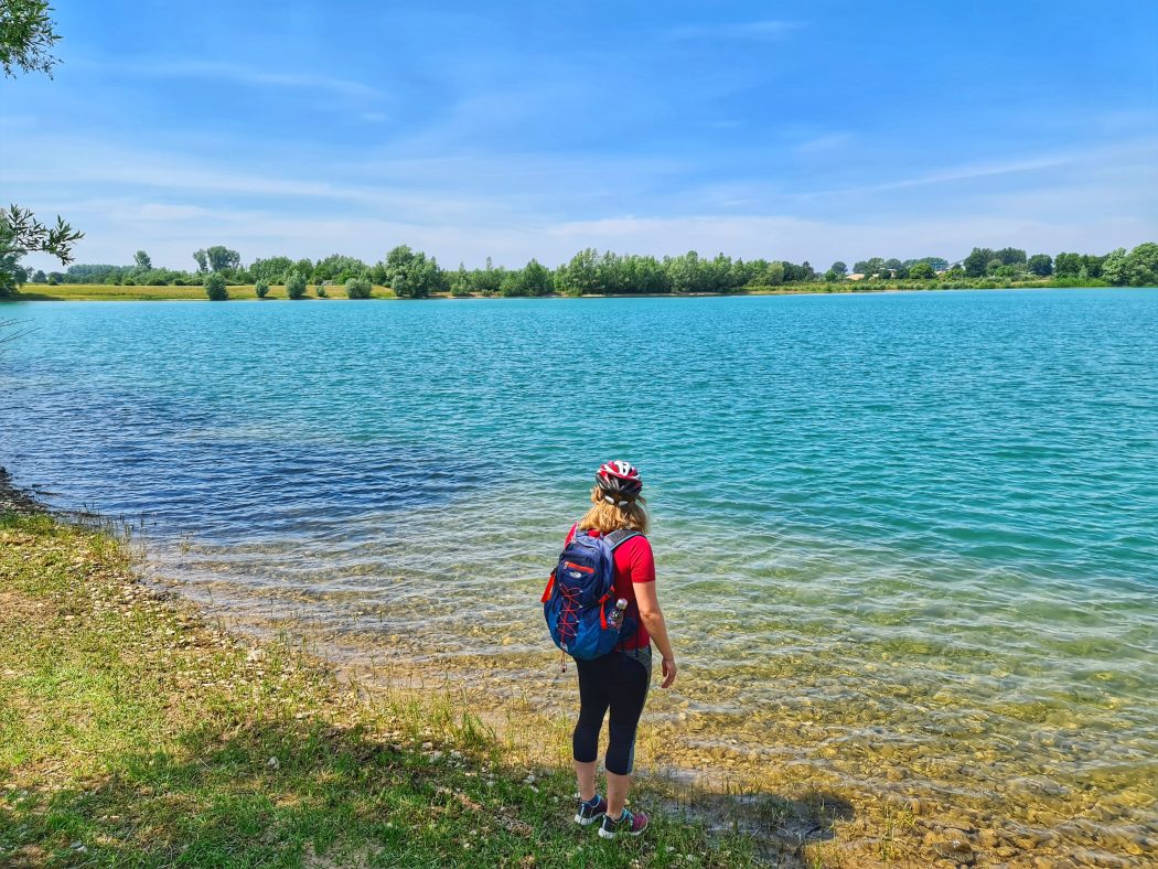 Das Foto zeigt eine Radfahrerin an einem Baggersee im Kreis Wesel