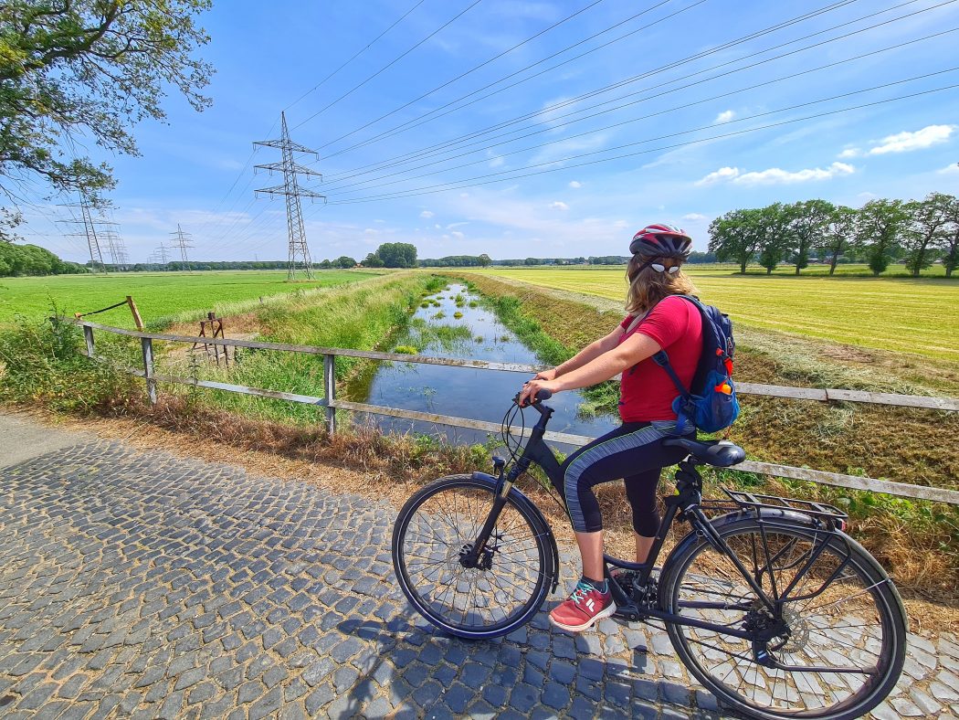 Das Foto zeigt eine Radfahrerin an der Issel im Kreis Wesel