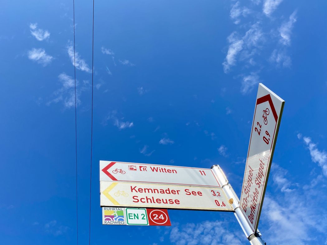 Das Foto zeigt ein Hinweisschild für Radfahrer samt Knotenpunkt und RuhrtalRadweg Einschub