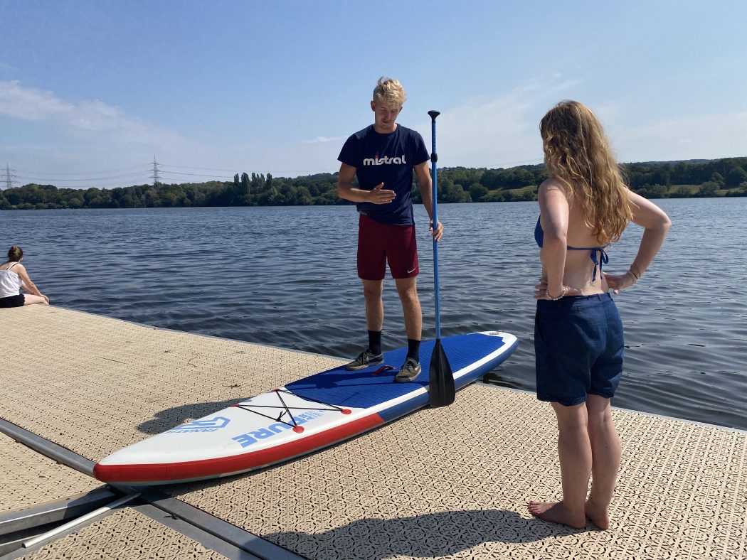Das Foto zeigt Rebecca mit SUP-Profi Timo Kersting an der Surfschule Westufer am Kemnader See
