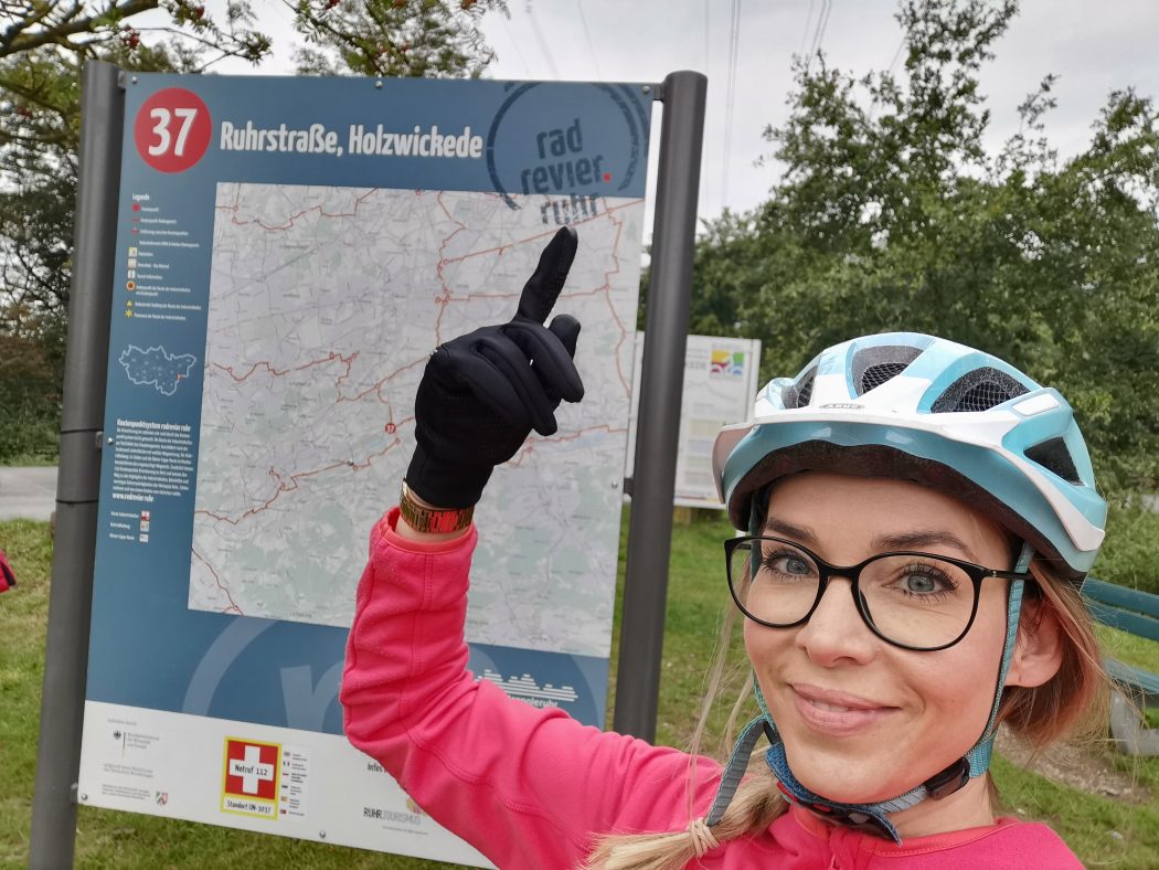 Das Foto zeigt Sandra an einer Knotenpunkttafel des radrevier.ruhr