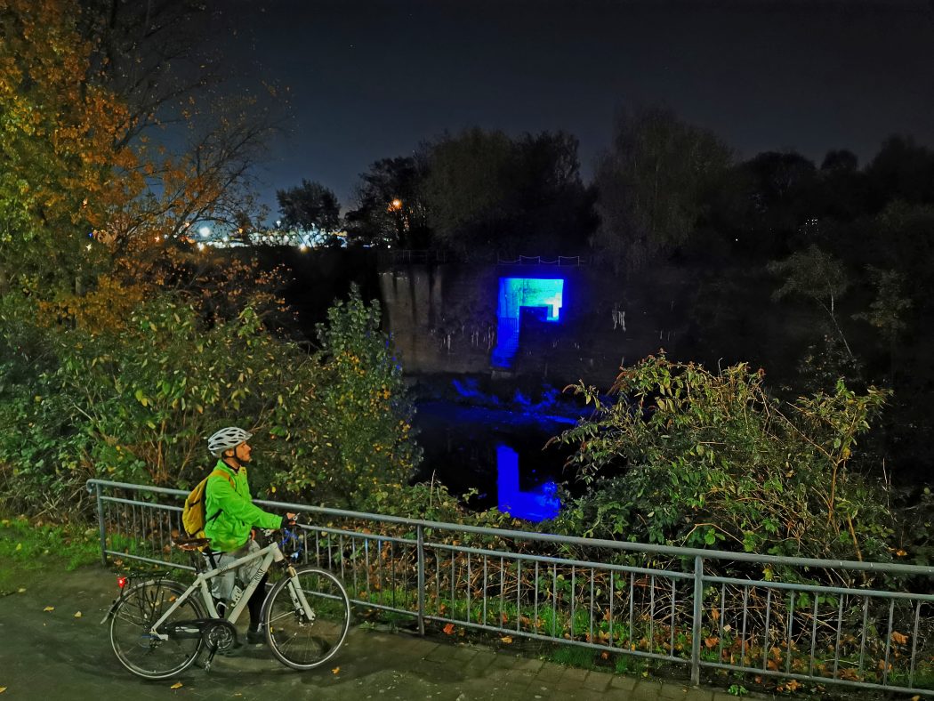 Das Foto zeigt einen Radfahrer in Dunkeln an der blauen Grotte in Duisburg