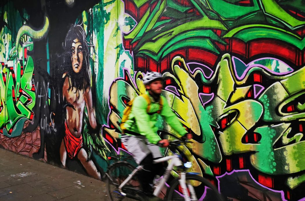 Das Foto zeigt einen Radfahrer vor einer Graffitiwand in Duisburg