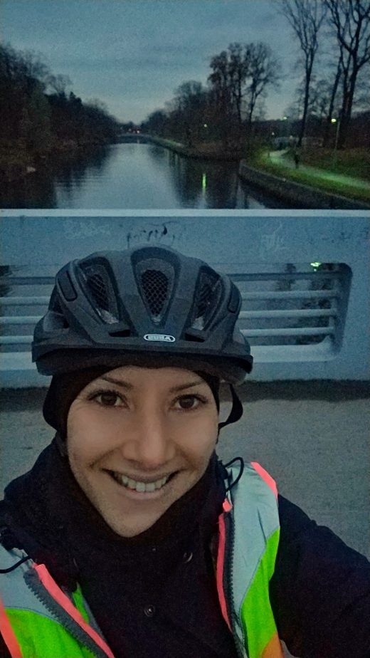 Das Bild zeigt eine Radfahrerin vor einem Kanal