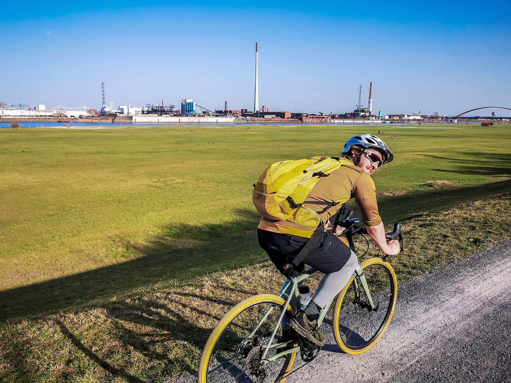 Das Foto zeigt einen Radfahrer auf dem Rheindamm in Duisburg