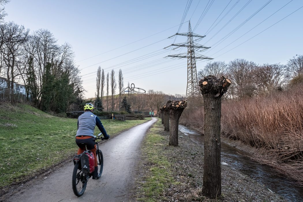 Das Foto zeigt einen Radfahrer kurz vor der Heinrich-Hildebrand-Höhe mit der Skulptur Tiger & Turtle in Duisburg