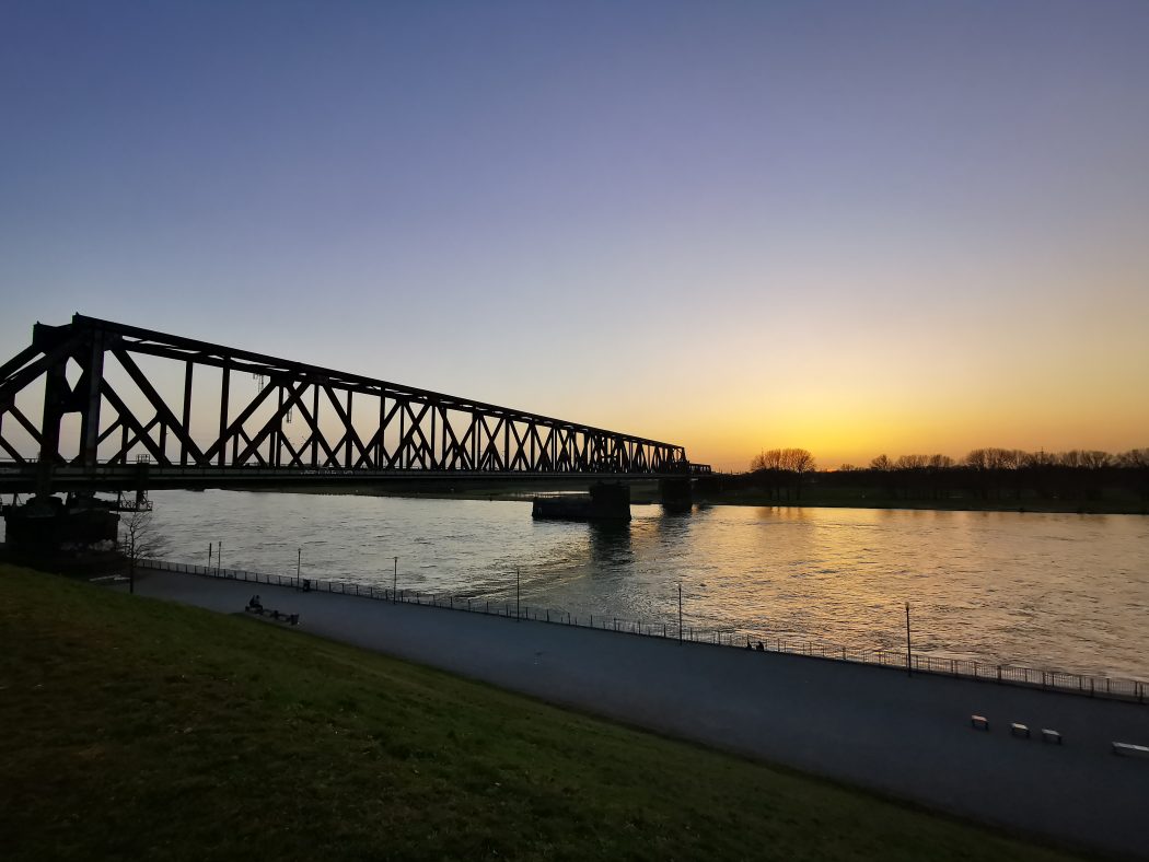 Das Foto zeigt die markante Eisenbahnbrücke in Duisburg-Wanheimerort bei Sonnenuntergang