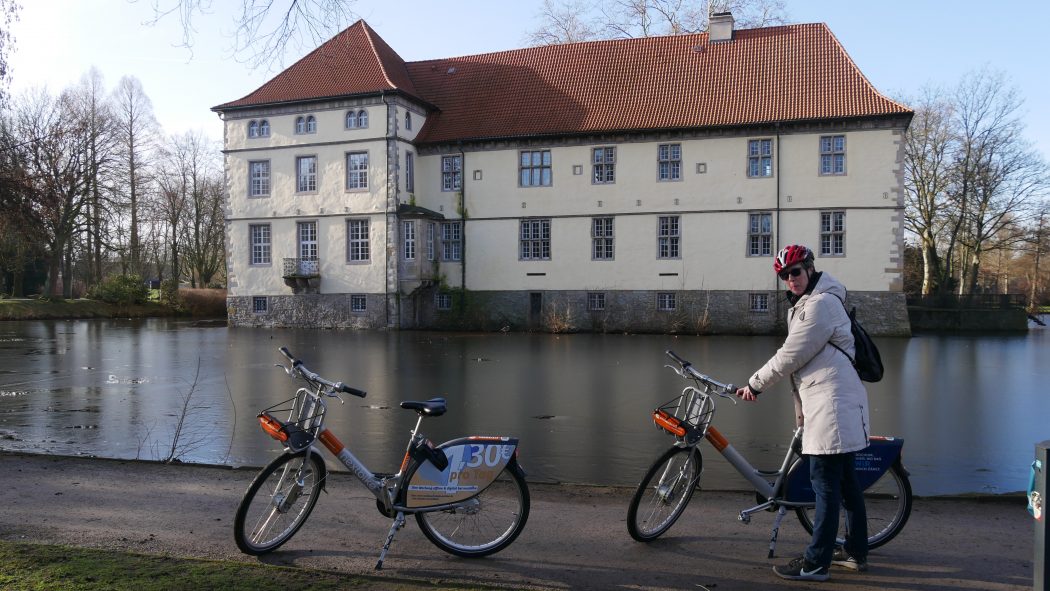 Das Foto zeigt eine Radfahrerin und zwei Fahrräder am Schloss Strünkede in Herne