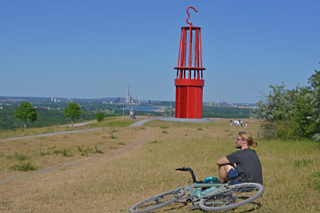 Das Foto zeigt einen Radfahrer auf der Halde Rheinpreußen mit dem Geleucht in Moers