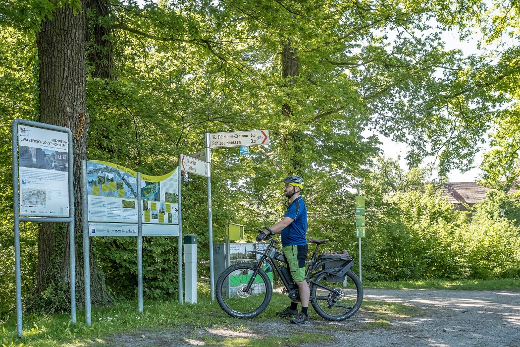 Das Foto zeigt Jochen vor Wegweisern des rot-weißen Radverkehrsnetzes