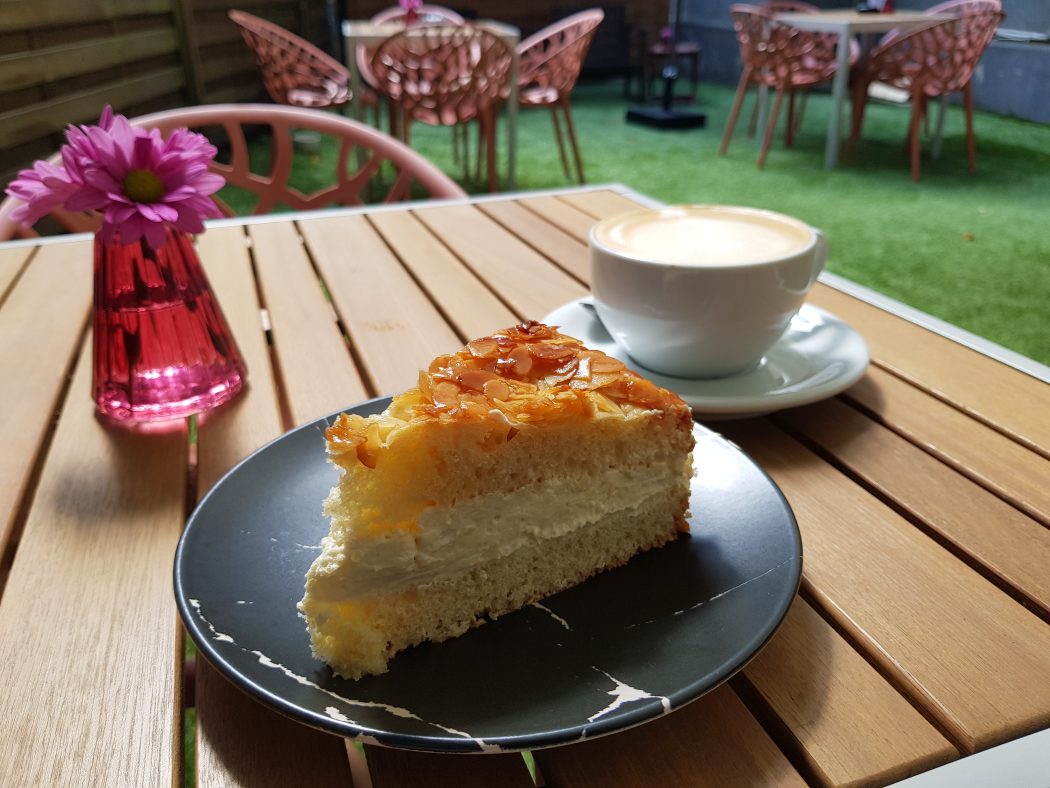 Das Foto zeigt veganen Bienenstich im gemütlichen Hinterhof des Café Rot in Dortmund