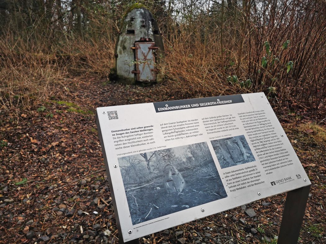 Das Foto zeigt eine Infotafel über den Einmann-Bunker neben der ehemaligen Krupp Werksbahn in Essen