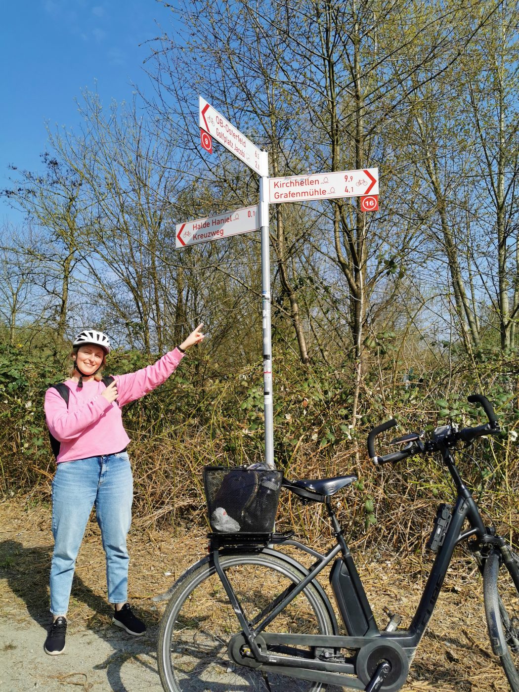 Das Foto zeigt Katalina an einem Radverkehrshinweisschild an der Halde Haniel in Bottrop
