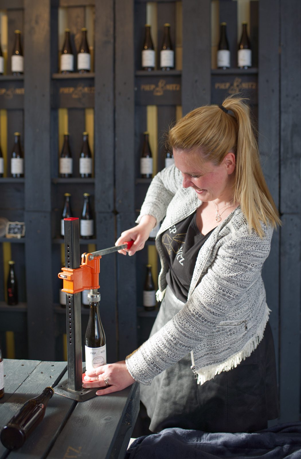 Das Foto zeigt Stella Golzwarden, die Inhaberin der Piepnitz Craft Beer Brauerei in Bochum beim manuellen Verschließen einer Bierflasche