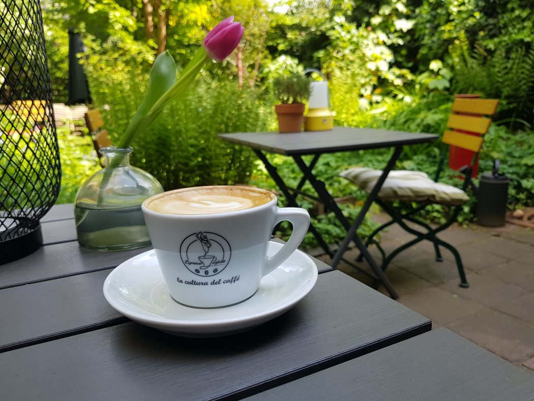 Das Foto zeigt einen Cappuccino im Hinterhof des WinzigSchön in Duisburg