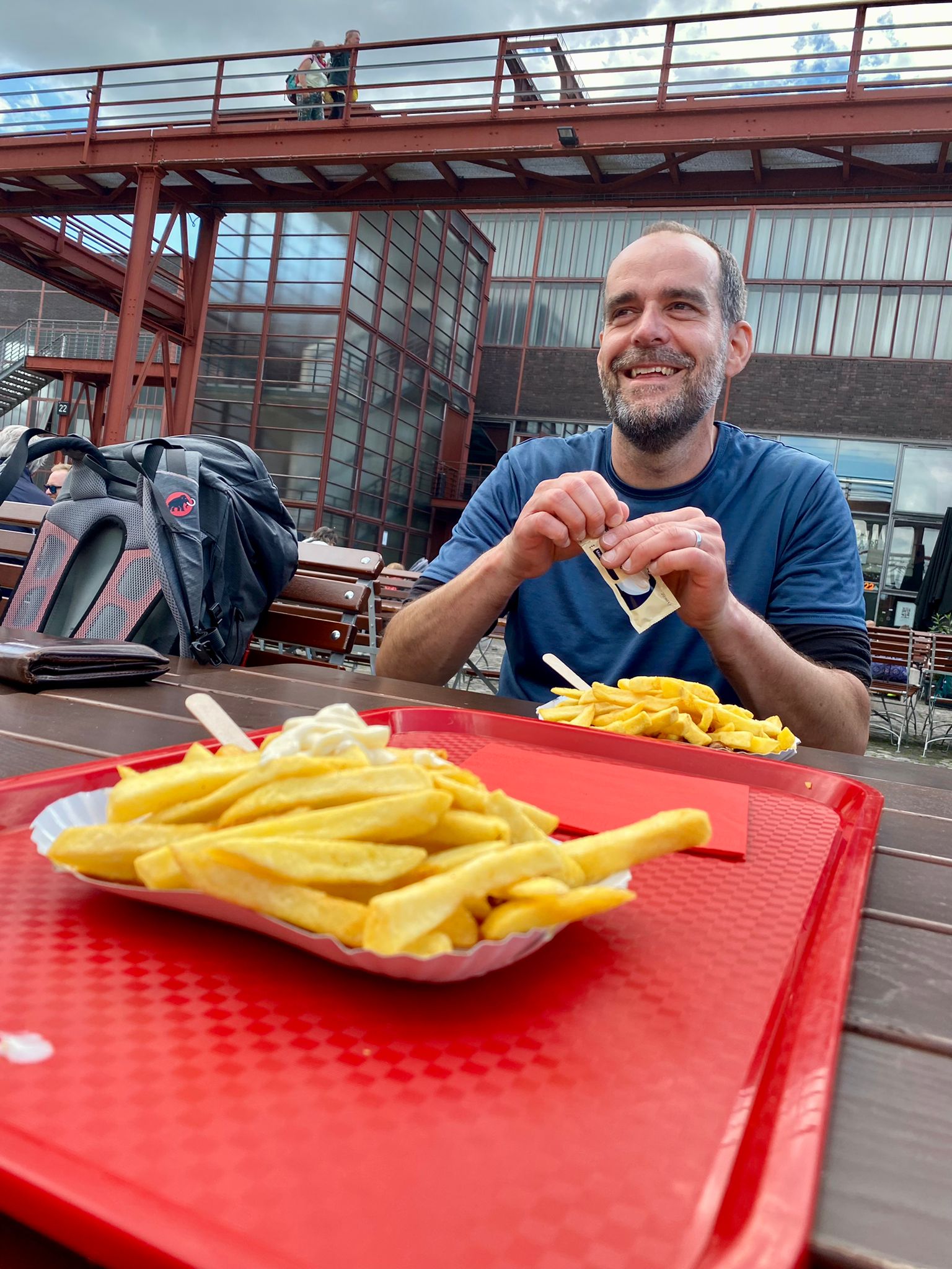 Das Foto zeigt Christoph mit Currywurst und Pommes auf dem Gelände der Zeche Zollverein