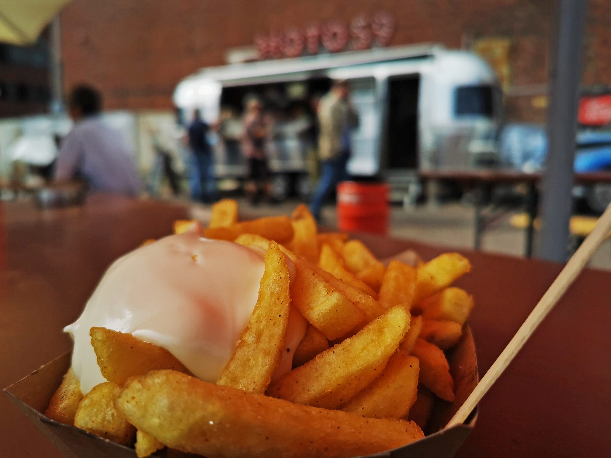 Das Foto zeigt Currywurst Pommes des Foodtrucks Moto59 auf dem Geländer der Zeche Ewald in Herten zum Abschluss der Gravel.Trail.Tour durch die Brauker Alpen