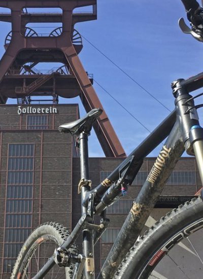 Das Foto zeigt ein Mountainbike vorm Doppelbock des UNESCO-Welterbe Zollverein in Essen.