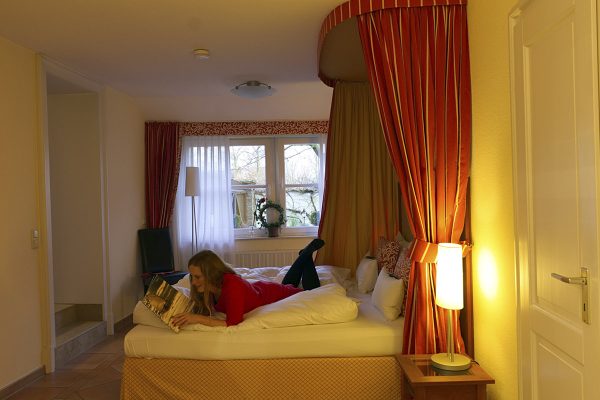 Das Foto zeigt Rebecca beim Lesen im Himmelbett des Wellings Romantik Hotel zur Linde in Moers