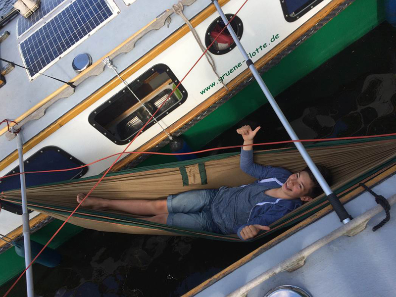 Das Bild zeigt einen Jungen in einer Hängematte auf einem Hausboot