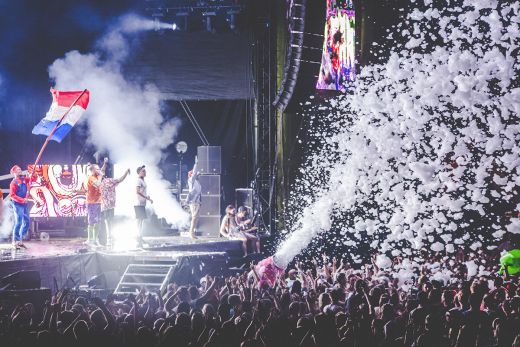Das Bild zeigt eine Bühne, auf der eine Band performt mit Schaumkanone davor.