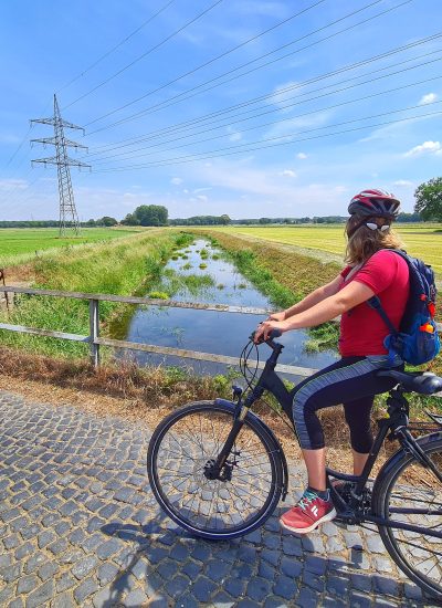 Das Foto zeigt eine Radfahrerin an der Issel im Kreis Wesel