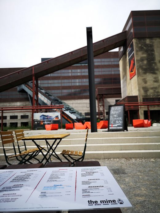 Das Bild zeigt die Karte eines Restaurants vor industriekultureller Kulisse