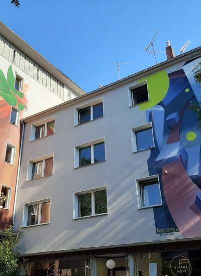 Das Foto zeigt eiin Mural von Zone56 auf einer Hausfassade an der Alten Hattinger Straße 11.