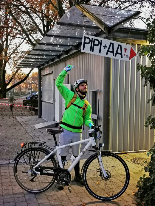 Das Foto zeigt einen Radfahrer am Schild "PIPI + AA" im Kaisergarten Oberhausen