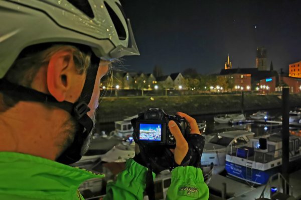 Das Foto zeigt einen Radfahrer beim Fotografieren im dunklen Innenhafen Duisburg