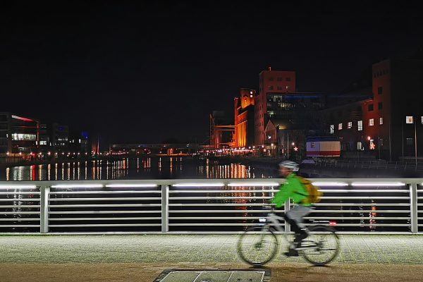 Das Foto zeigt einen Radfahrer in der Nacht im Innenhafen Duisburg