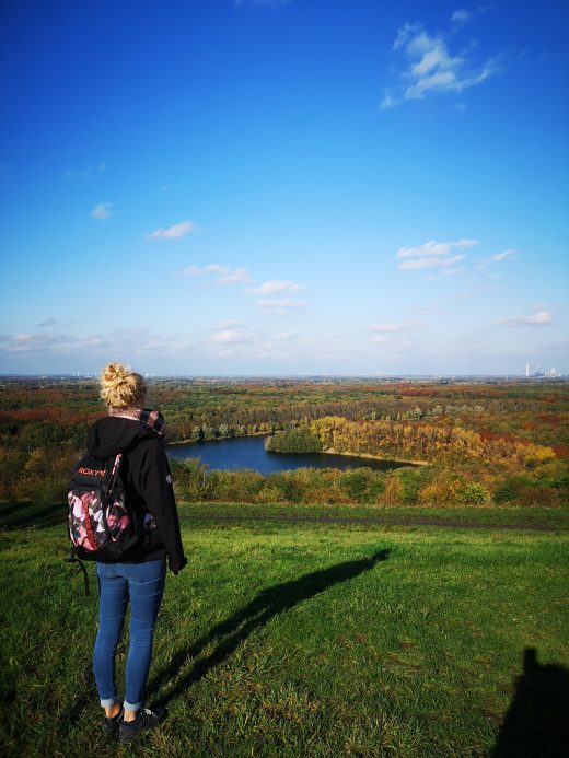 Das Bild zeigt eine Frau von hinten mit Blick auf einen See