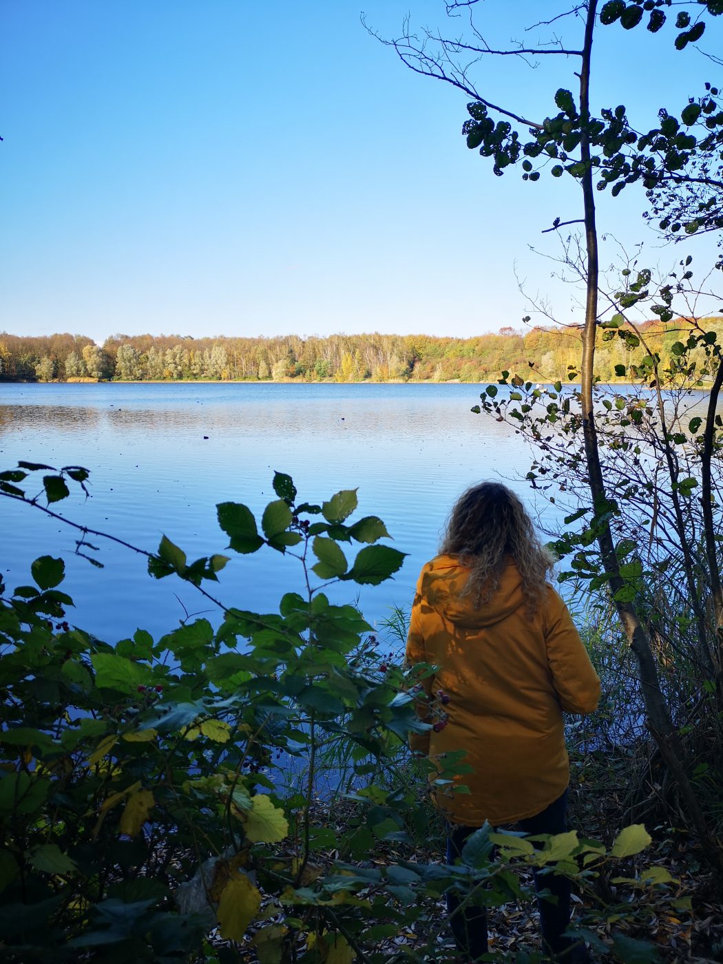 Das Bild zeigt eine Frau an einem See