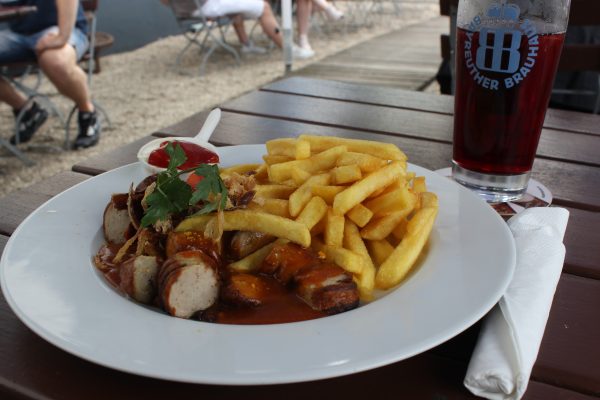 Das Foto zeigt Currywurst Pommes im Biergarten des Bootshaus Ruhreck in Essen-Steele