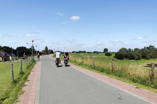 Das Foto zeigt zwei Radfahrer auf dem Rheindamm in Xanten, der oberhalb des "Unser Lieblingscafé" verläuft