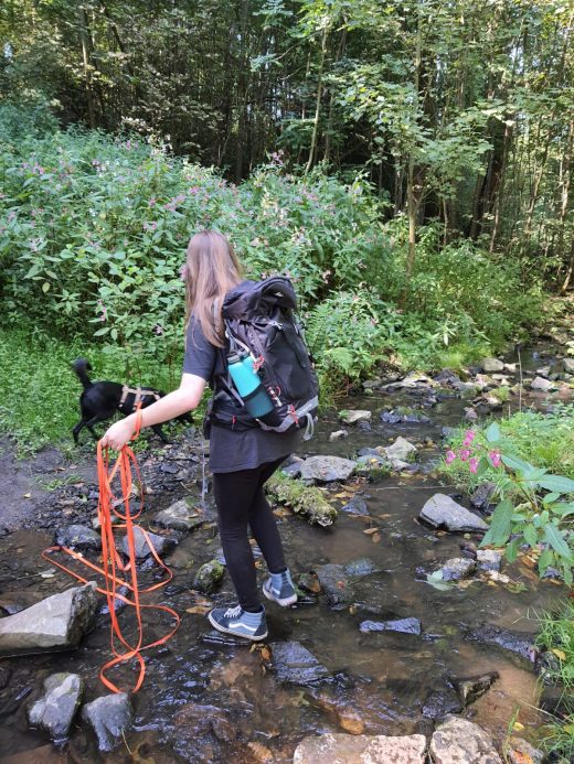 Das Foto zeigt Melissa mit ihrem Hund an einem Bach auf dem Kettwiger Panoramasteig