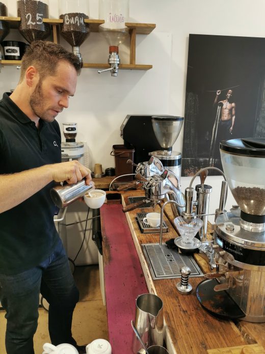 Das Foto zeigt Simon, den Betreiber der Kaffeerösterei Bristoteles in Bochum, bei der Zubereitung eines Cappuccinos