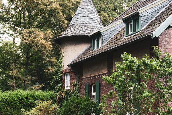 Das Bild zeigt ein Eckhaus mit Turm in der Siedlung Rheinpreußen