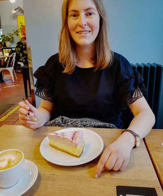 Das Foto zeigt Melissa mit Cappuccino und Kuchen im Café Lotte im Kaiserviertel in Dortmund