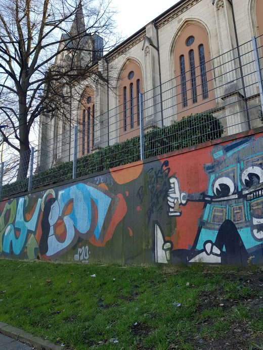 Das Foto zeigt eine weitere Graffiti Wall vor einer Kirche in Essen